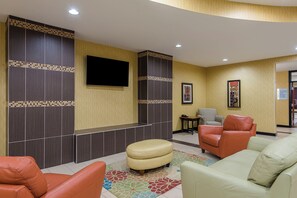 Un hall d’entrée avec des sièges, un téléviseur à écran plat et un mur décoré de motifs.