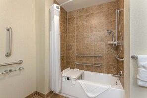 Une salle de bain équipée d’une baignoire, d’une douche et de barres d’appui.