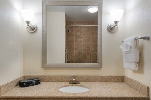 Une salle de bain avec un miroir rectangulaire, un lavabo et un porte-serviettes.