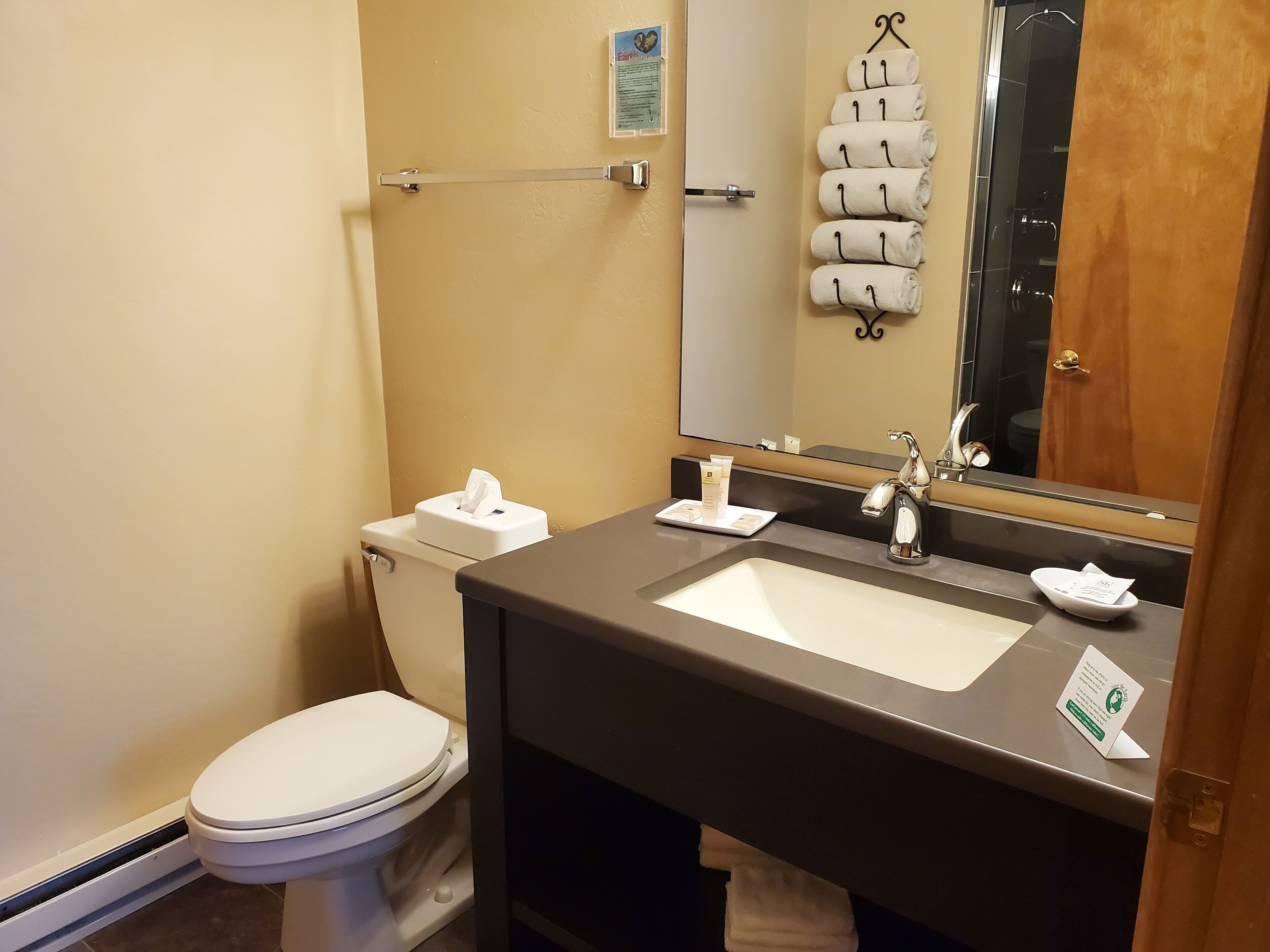 A bathroom with a white toilet, a sink with a mirror, and a towel rack with towels.