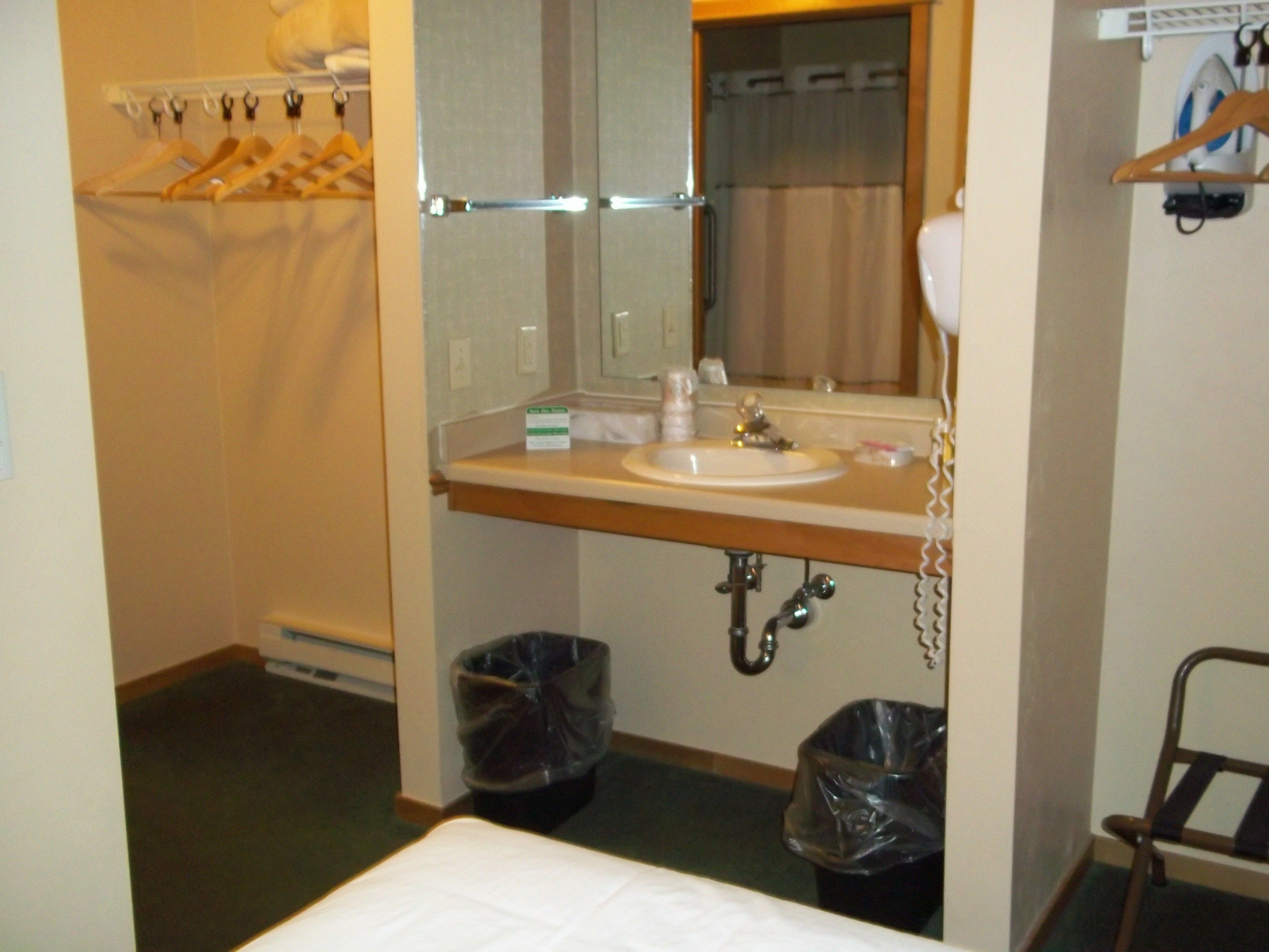 A hotel bathroom with a sink, mirror, and two trash bins.