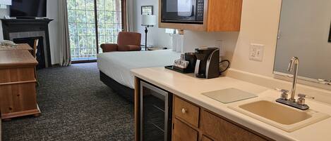 Habitación de hotel con cama, escritorio, televisión, microondas, cafetera y lavamanos.