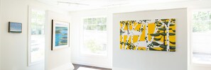 An art gallery with framed paintings on the walls and large windows allowing natural light. - Grand Hotel (Kennebunk)