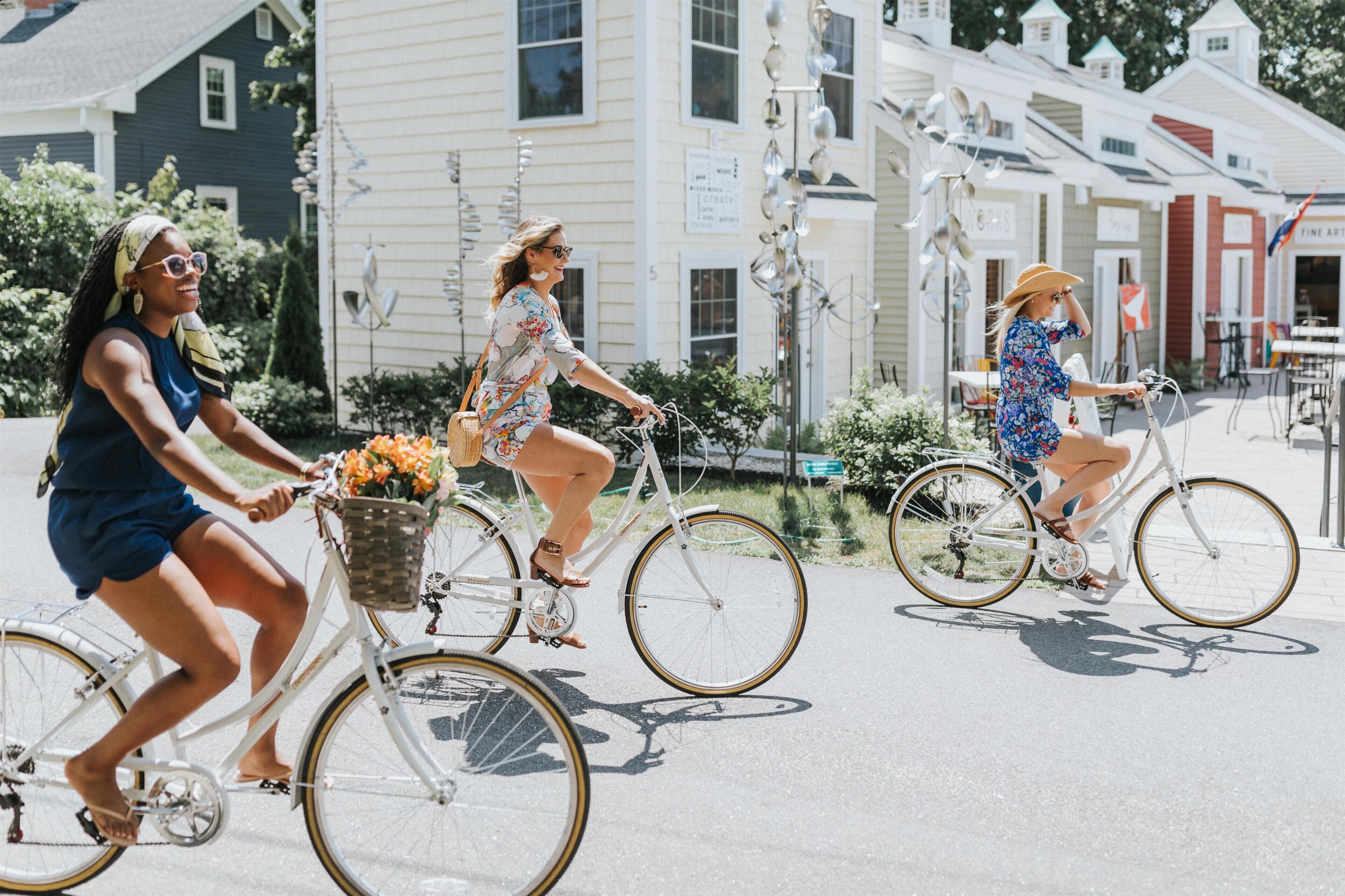 Tres mujeres andan en bicicleta por una calle soleada.