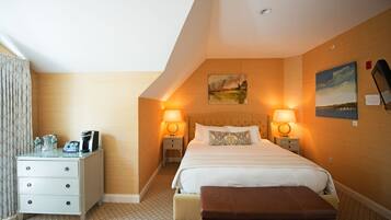 Una habitación de hotel con cama, mesitas de noche, un banco y obras de arte en las paredes.