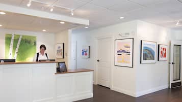 A reception area with a wooden reception desk, framed artwork on the walls, and a door leading to another room.