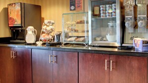 Un bancone da cucina con una macchina per il caffè, una vetrina con dolci e un frigorifero pieno di cibo.