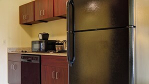 Una cucina con frigorifero nero, mobili in legno, lavastoviglie e forno a microonde.