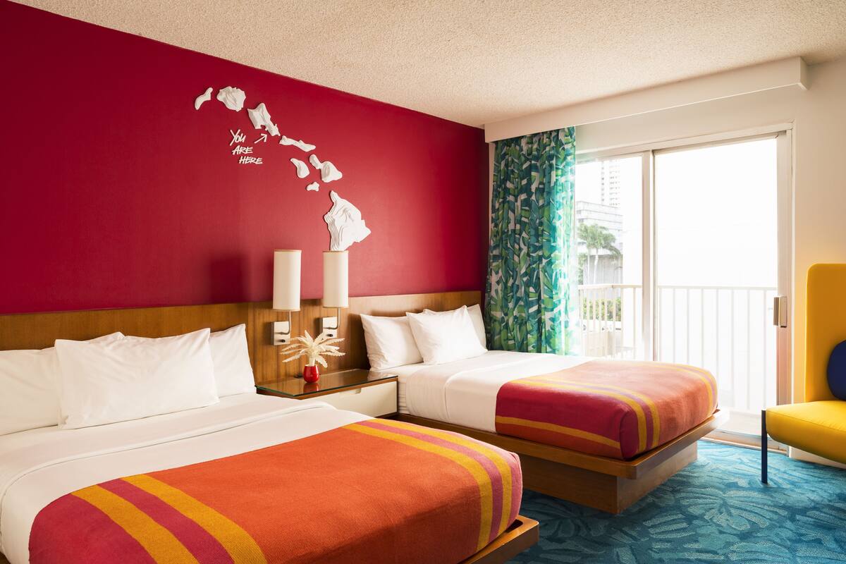 A hotel room with two beds, a red wall with a map, a balcony with a view, and a tropical-themed carpet.