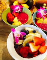 Postre con fresas, plátanos, arándanos y salsa roja, decorado con una orquídea púrpura.
