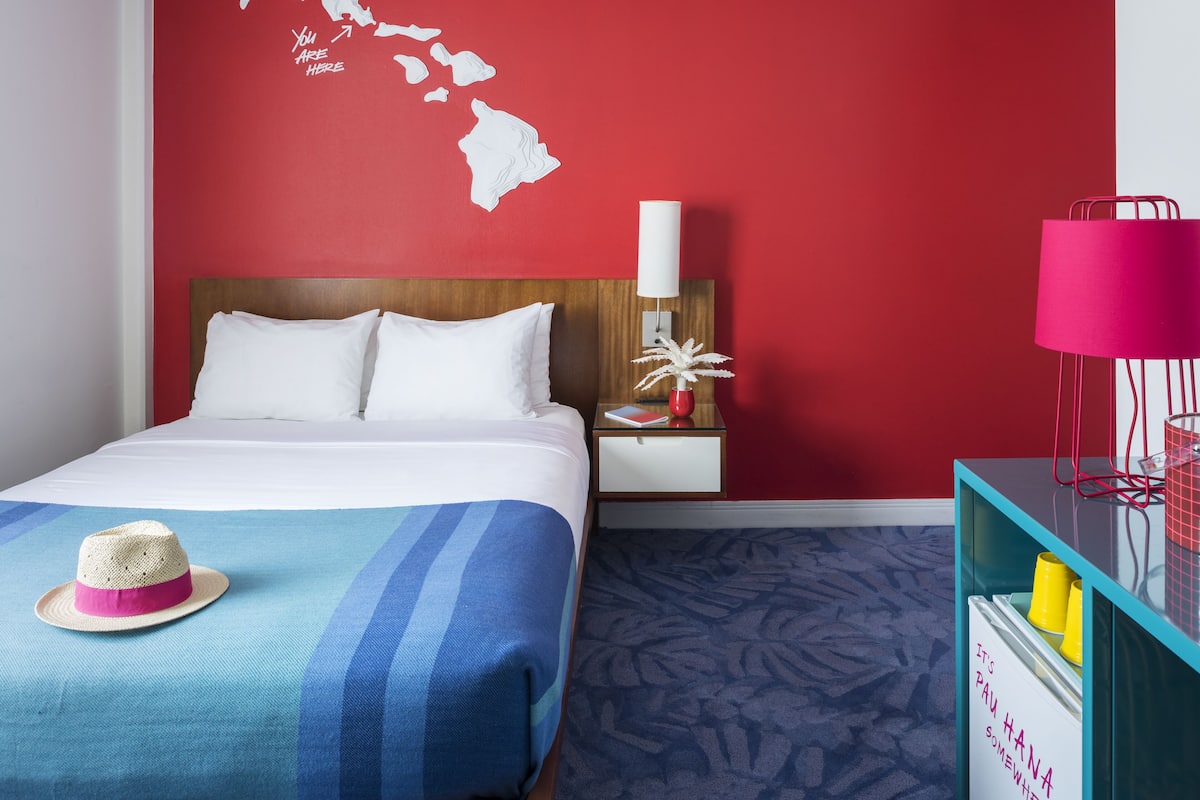 A hotel room with a bed, a nightstand, a lamp, and a decorative map on the wall.