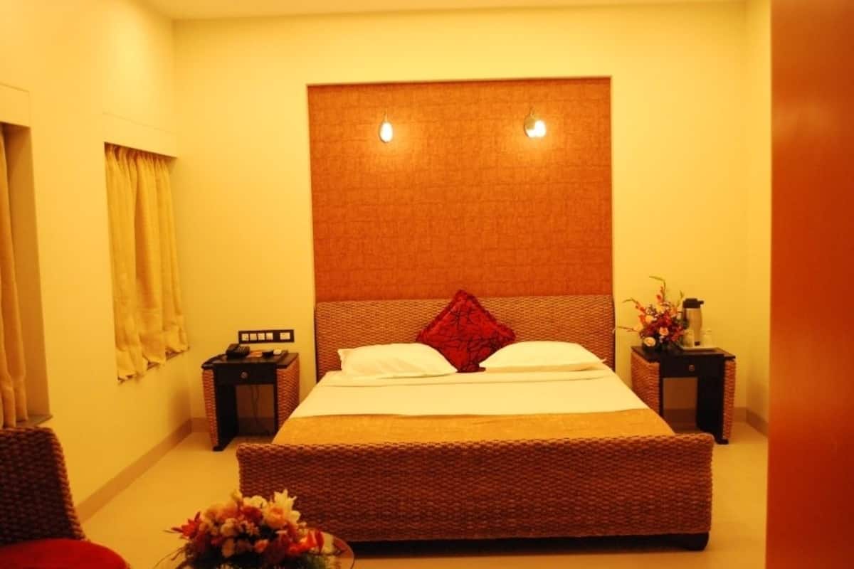 Ein ordentlich eingerichtetes Schlafzimmer mit einem großen Bett, zwei Nachttischen und einem kleinen Tisch mit Blumen.