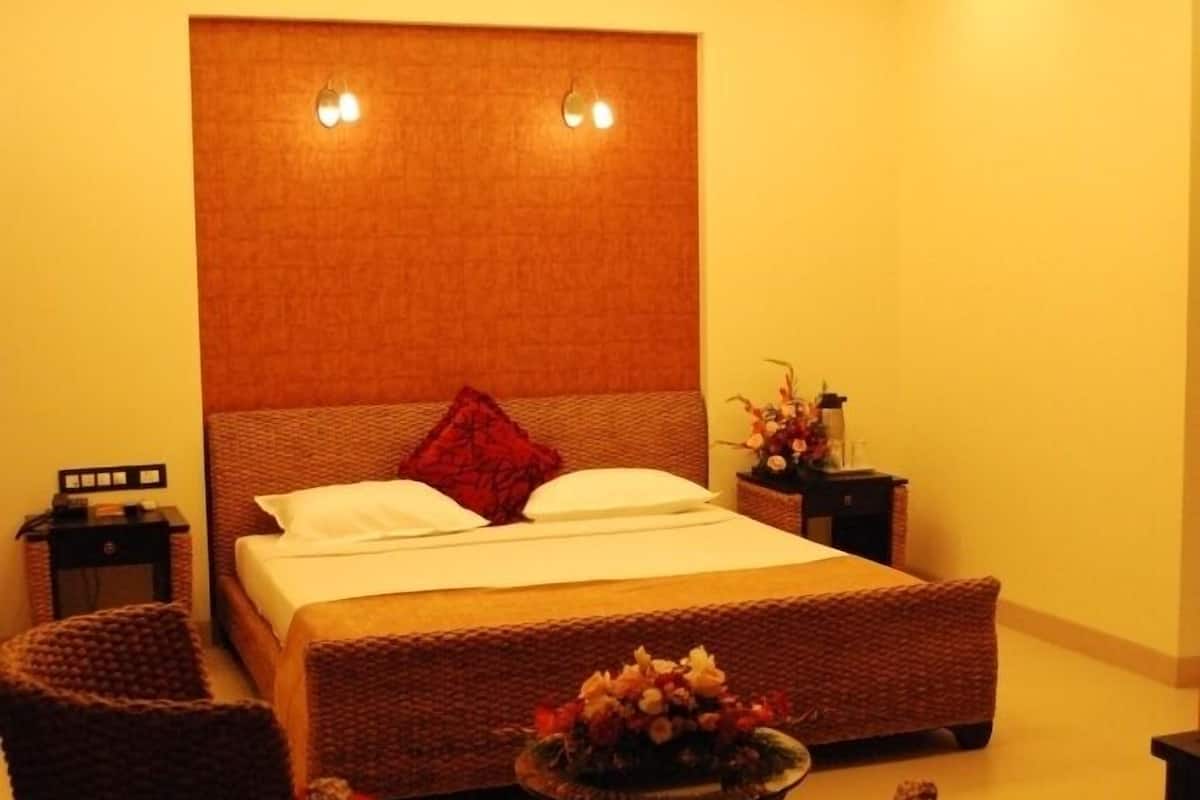 Ein Schlafzimmer mit einem Bett, zwei Nachttischen, einem Deckenventilator, einem kleinen Tisch mit Blumen und Korbstühlen.