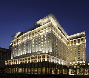 A multi-story hotel with a modern architectural design, featuring a prominent rooftop structure and illuminated windows.