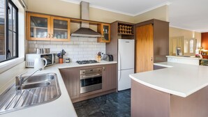 Una cocina moderna con un lavamanos de acero inoxidable, horno empotrado, microondas y armarios de madera.