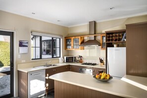 Una cocina moderna con lavavajillas, microondas, estufa y un tazón de fruta en la encimera.