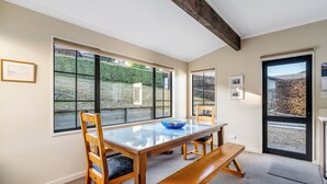 Un comedor con una mesa de vidrio, sillas de madera y un banco.