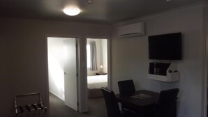 Ein Hotelzimmer mit Essbereich, einem an der Wand befestigten Fernseher und einer Klimaanlage.