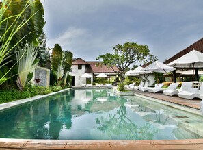 Una piscina al aire libre, sombrillas, sillones reclinables de piscina