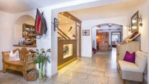 A spacious living area with a wooden bench, a sofa, and a decorative mirror. - Hotel Garni Lavendel (Lech am Arlberg)