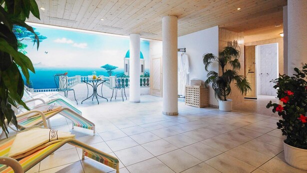 A spacious indoor area with a tiled floor, a balcony with a view of the sea, and a seating area with a table and chairs. - Hotel Garni Lavendel (Lech am Arlberg)