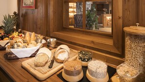 A wooden interior with a buffet table displaying various breads, cheeses, and fruits. - Haymon (Seefeld in Tirol)