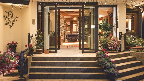 A hotel entrance with a stone facade, glass doors, and a staircase leading to the entrance. - Haymon (Seefeld in Tirol)