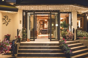 L’entrée d’un hôtel, avec une façade en pierre, des portes en verre et un escalier menant à l’entrée.