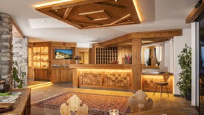 A cozy, rustic interior with a wooden reception desk, stone walls, and a large rug. - Haymon (Seefeld in Tirol)