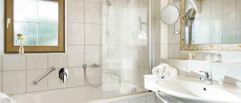 A modern bathroom with a bathtub, shower, and sink.
