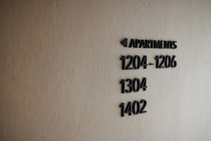 A wall with apartment numbers and an arrow pointing left, indicating the direction to the apartments.