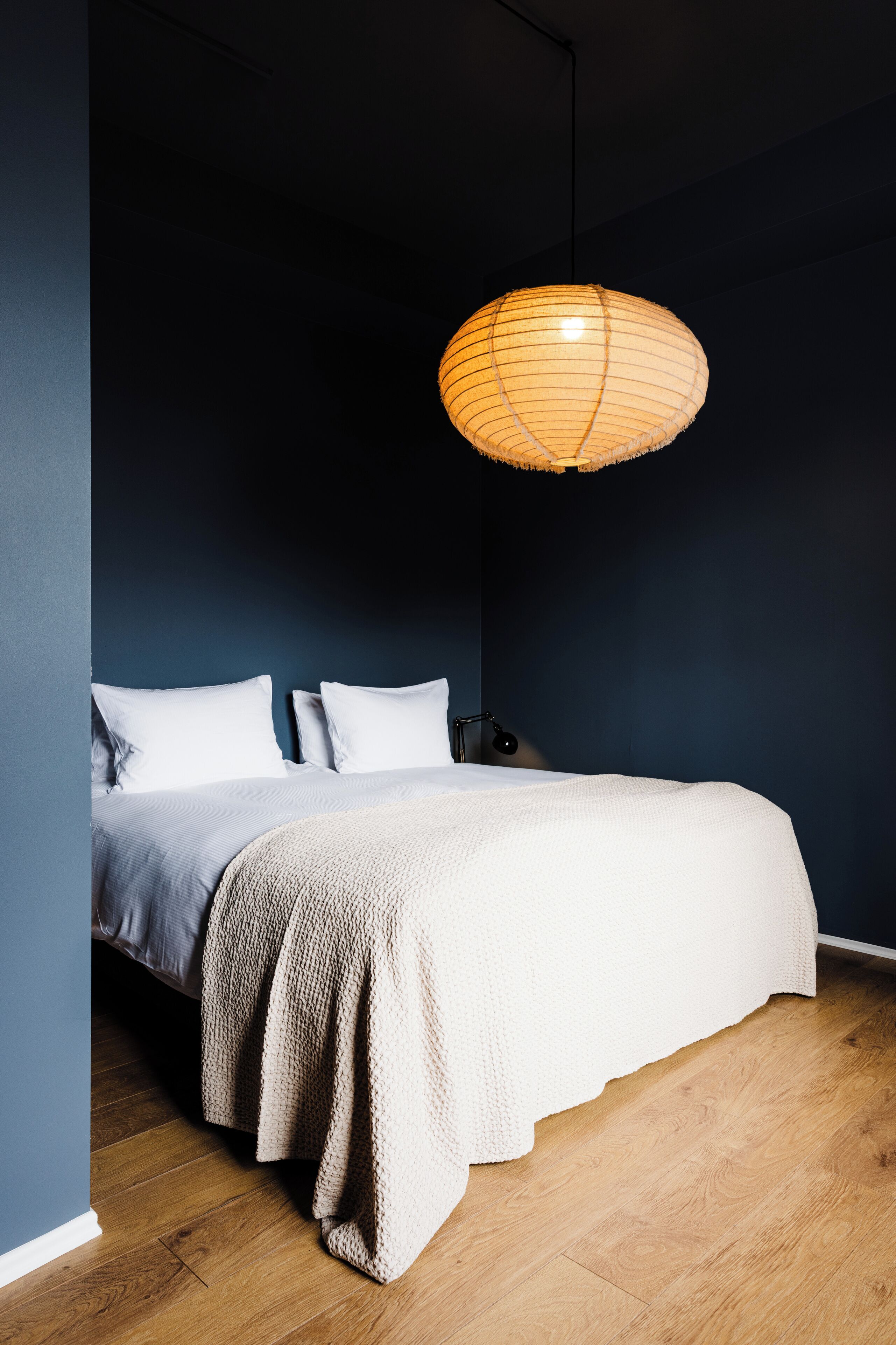 Une chambre à coucher comprenant un lit, une table de chevet, une lampe et un luminaire suspendu.