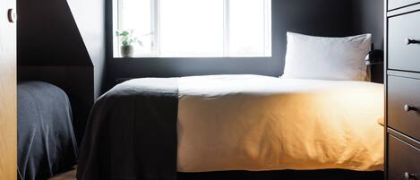 Une chambre à coucher avec un lit, une fenêtre et une commode.