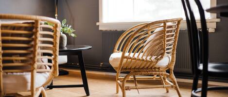 Wicker chairs with cushions, a small table with a plant, and a window with a view.