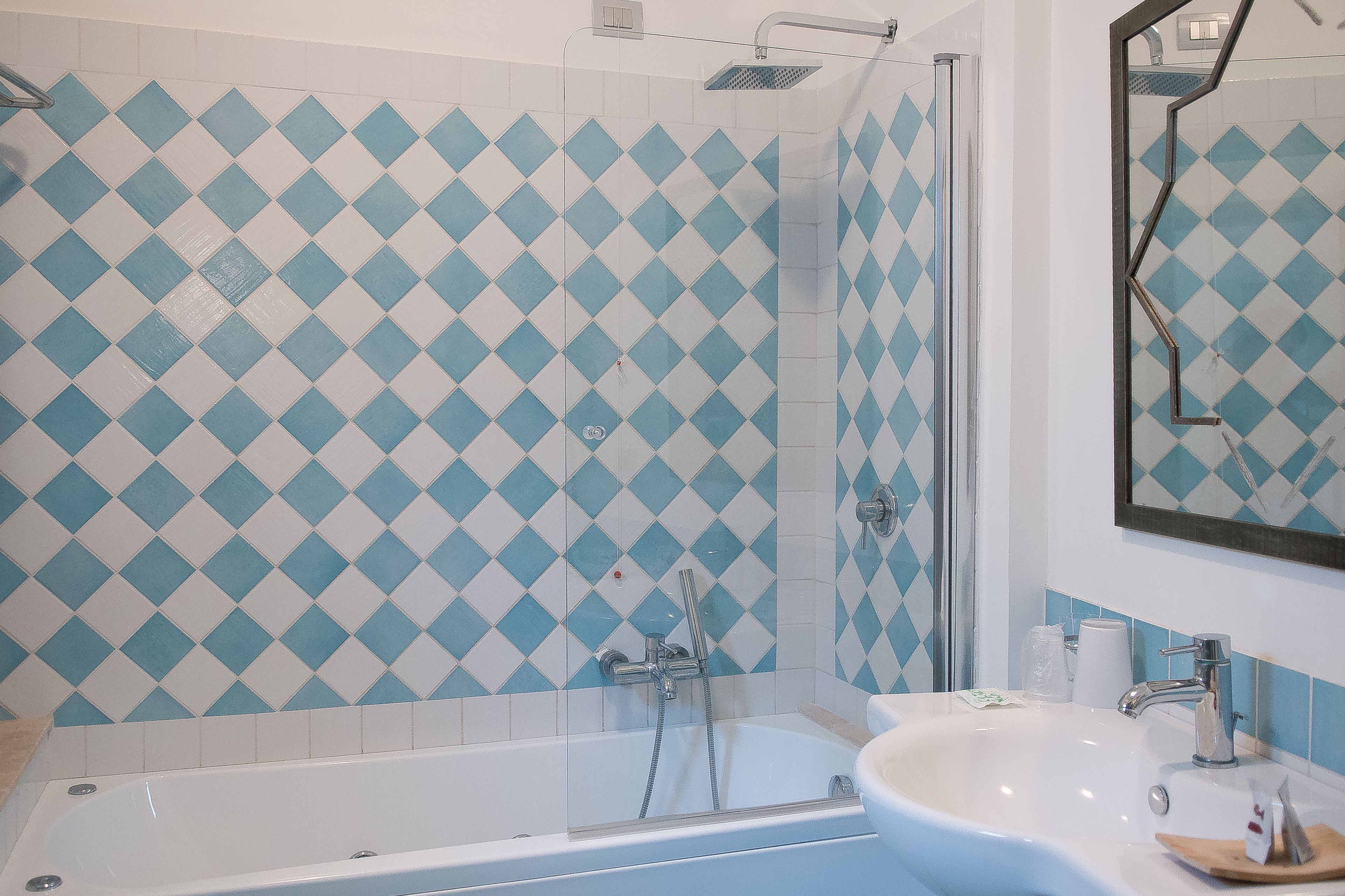 Een badkamer met een douche, een wastafel en een spiegel.