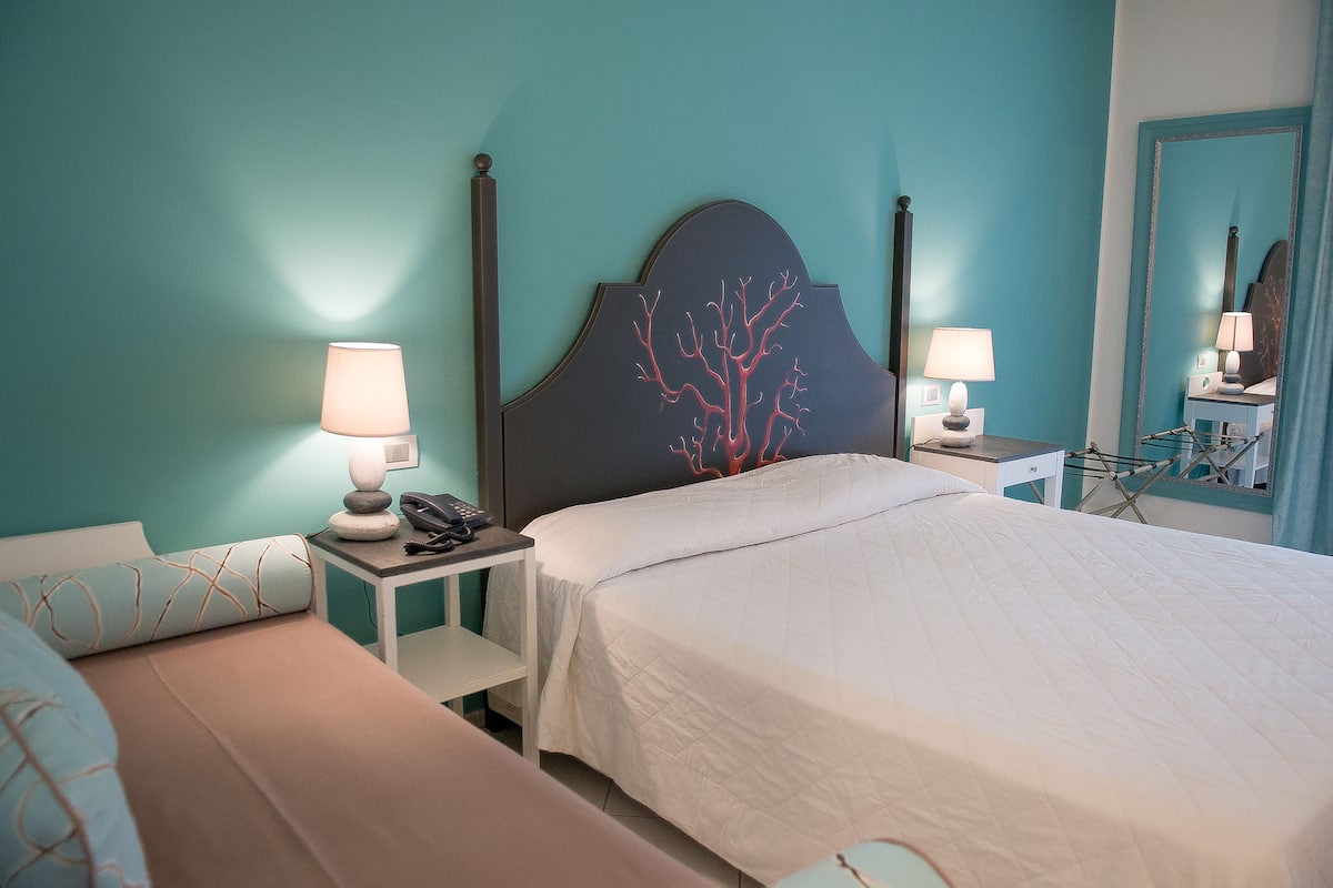 A bedroom with a bed, bedside tables, lamps, and a mirror.