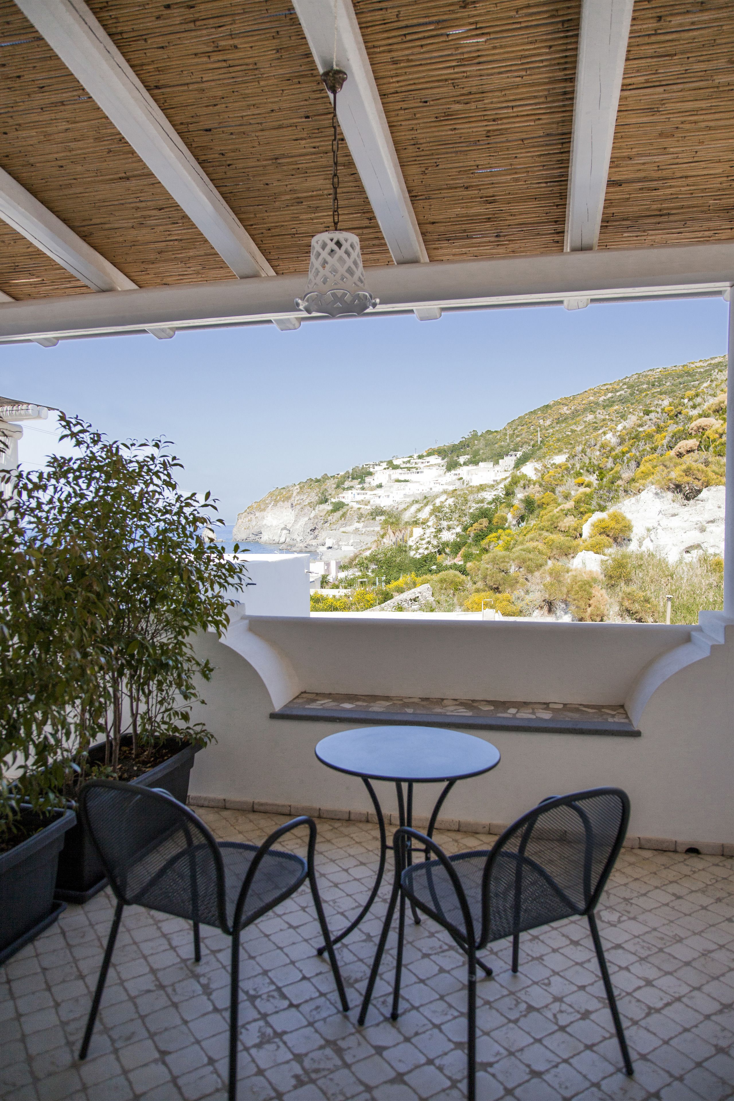 Un espacio de estar al aire libre cubierto, con una mesa y sillas, con vistas a un paisaje montañoso.