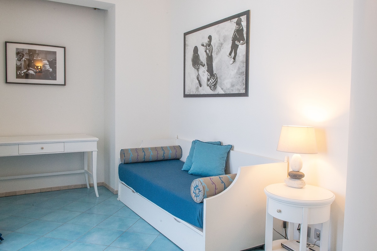 A room with a bed, a desk, and a wall-mounted lamp.