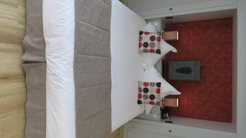 Een hotelkamer met een bed, twee kussens met stipjes, een nachtkastje, een lamp en een rode bakstenen muur.