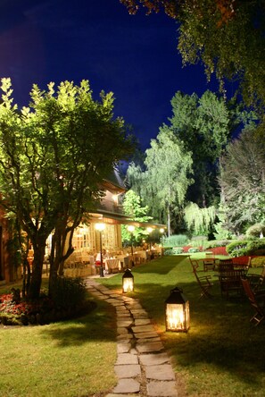 A garden pathway leading to a building with outdoor seating and lanterns. - Hotel de la Gaichel (Habscht)