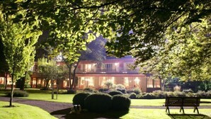 A well-lit hotel with a manicured lawn, a bench, and a pathway leading to the entrance. - Hotel de la Gaichel (Habscht)