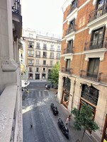 A street view with buildings, a tree, and parked scooters.