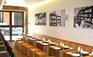 A dining area with tables set for meals, a window with a view of the street, and wall art.