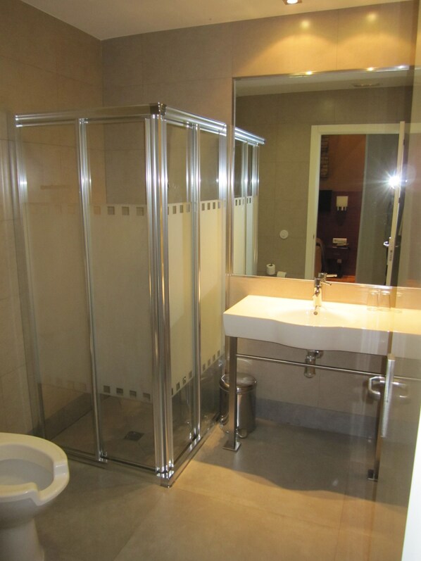 A bathroom with a glass-enclosed shower, a white sink, and a mirror above it.