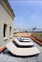 Eine Dachterrasse mit Liegestühlen und Meerblick.
