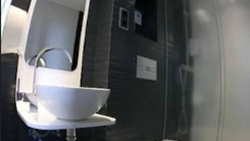 Un baño moderno con lavamanos blanco, espejo, inodoro y cabina de ducha.