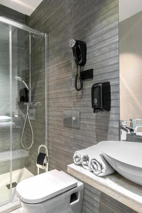 Un baño moderno con cabina de ducha de vidrio, un lavabo blanco y un perchero para toallas.