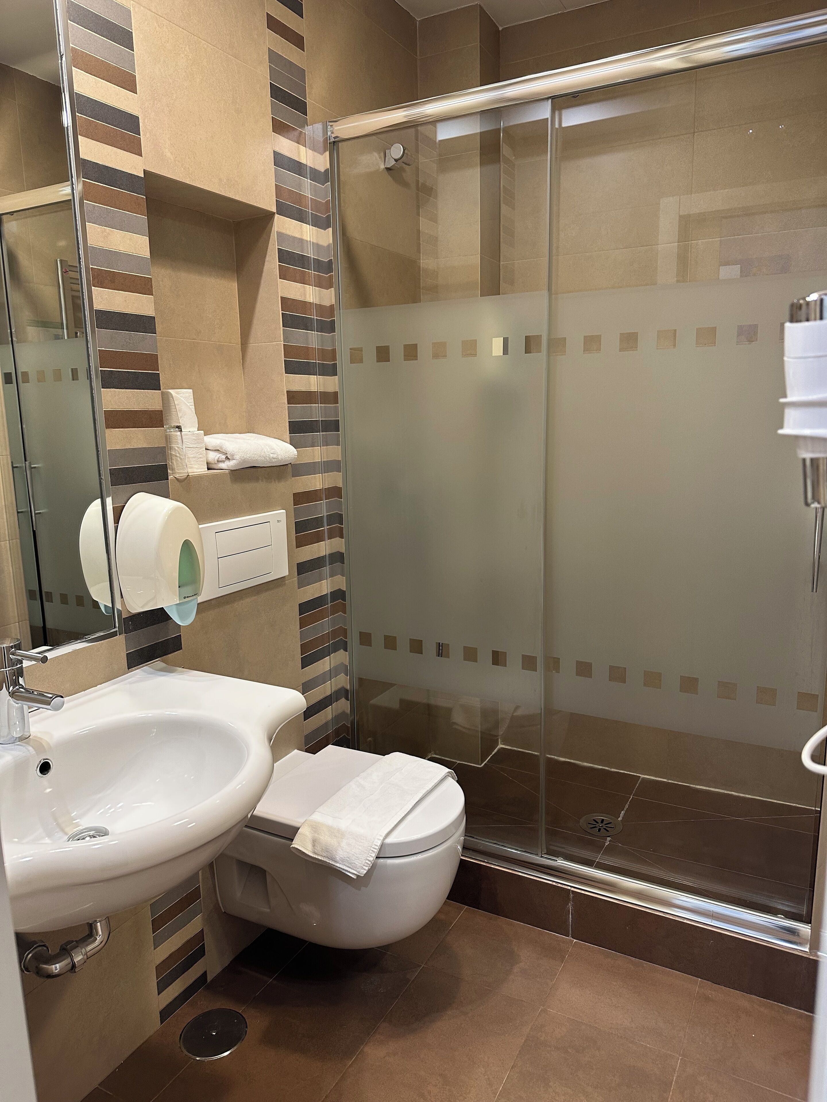 Une salle de bain avec une douche à parois de verre, un lavabo et des toilettes.