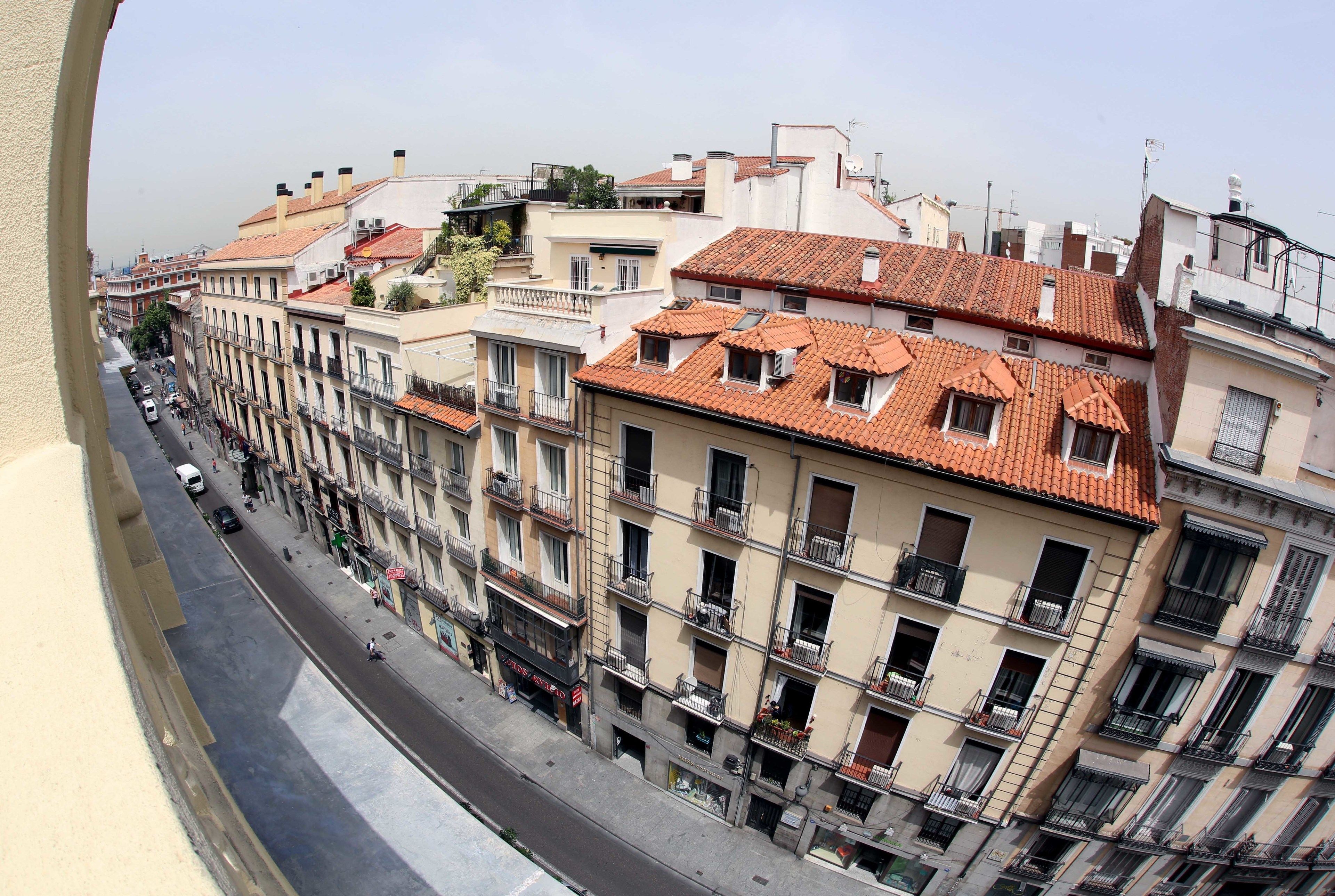 A multi-story building with balconies, a street in front, and a clear sky.