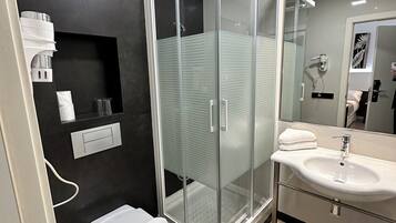 Un baño moderno con cabina de ducha de vidrio, lavabo e inodoro.